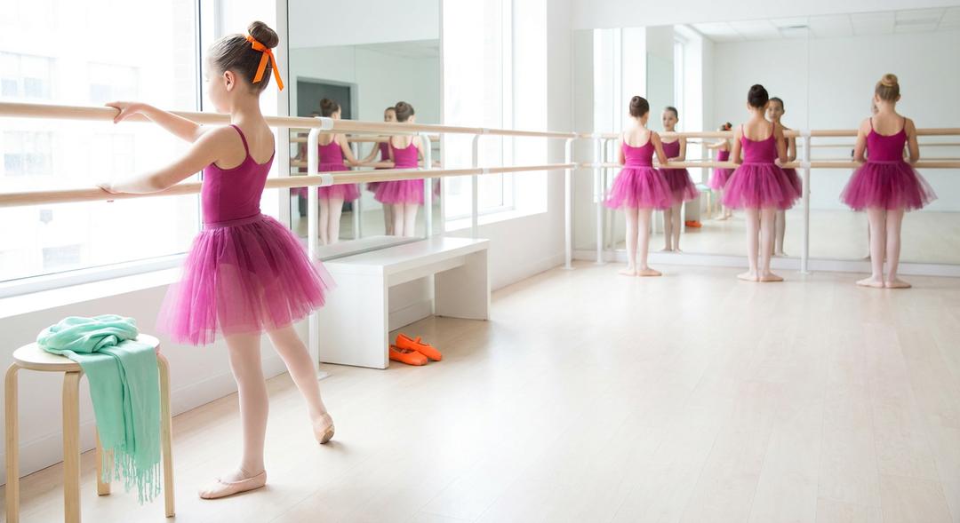 Young ballerinas practising at the barre in a ballet class