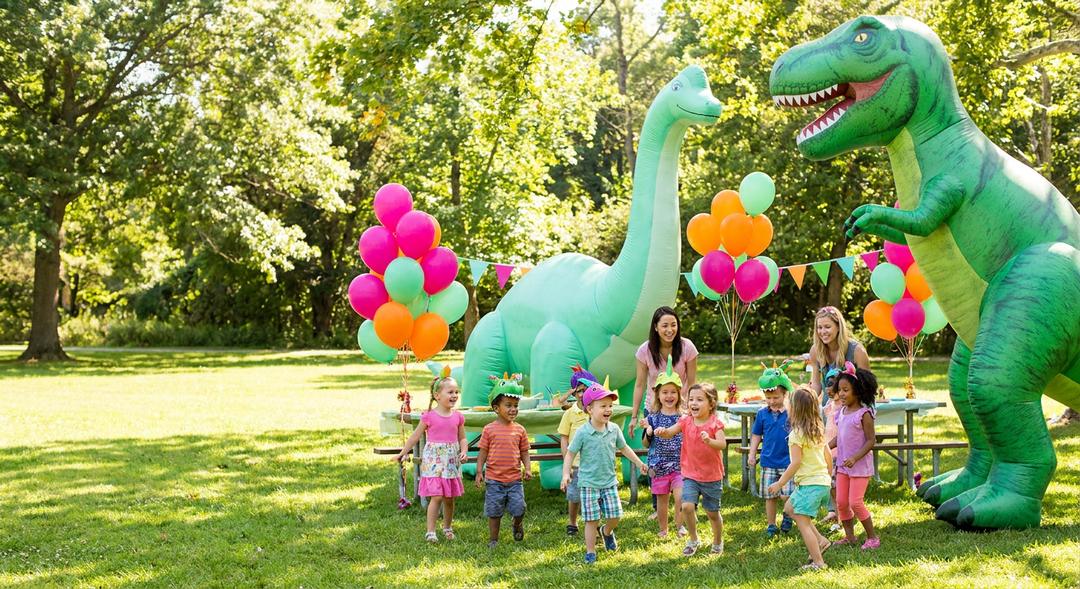 A kids' dinosaur-themed birthday party in the park with giant inflatable dinosaurs and balloons