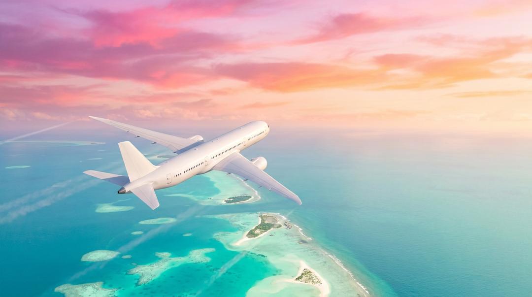 An airliner cruising over turquoise tropical islands at golden hour