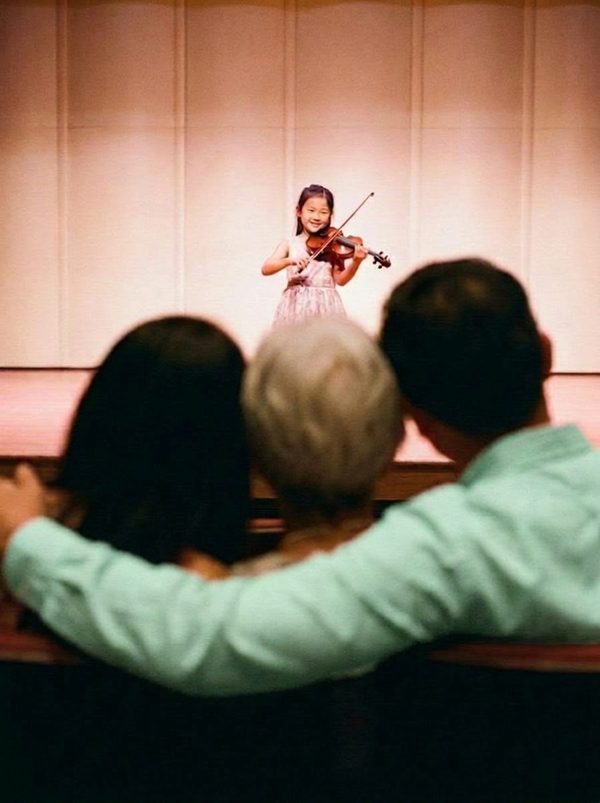 A family watching their child's school recital